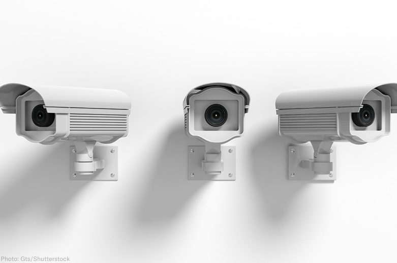 Three surveillance cameras on a wall point in three different directions giving the sense of a panopticon
