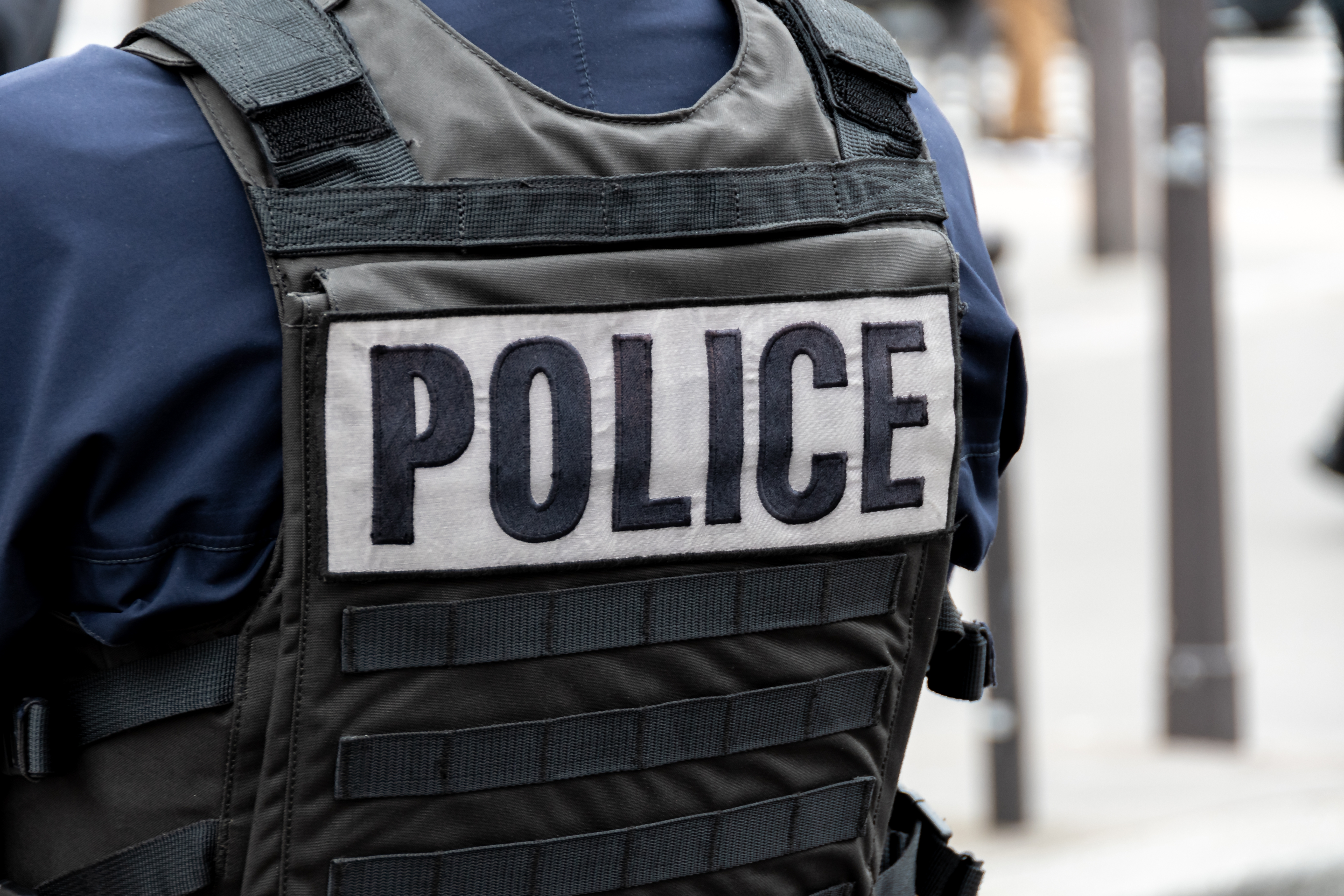 A person wearing a bulletproof vest with the word police across the back.
