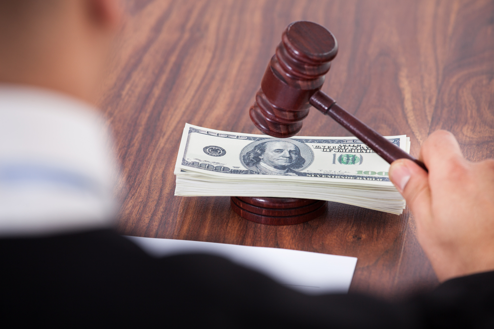Judge banging gavel on a pile of money.