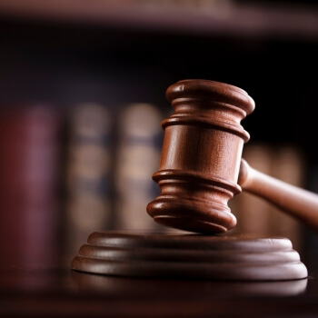 A gavel with a bookcase behind it. 