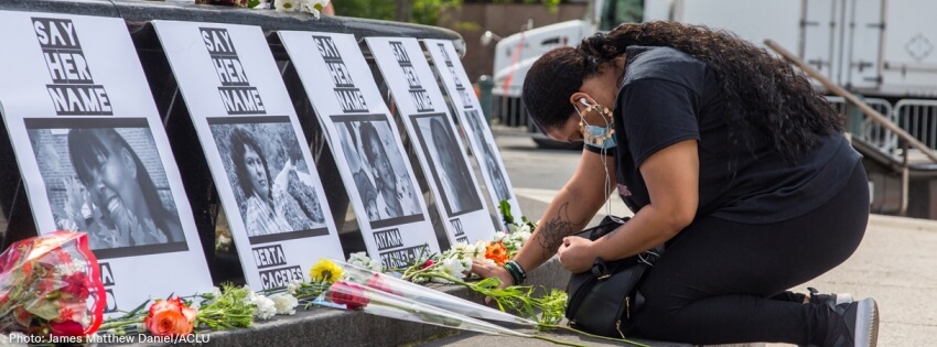 Person kneeling among portraits of people killed by police