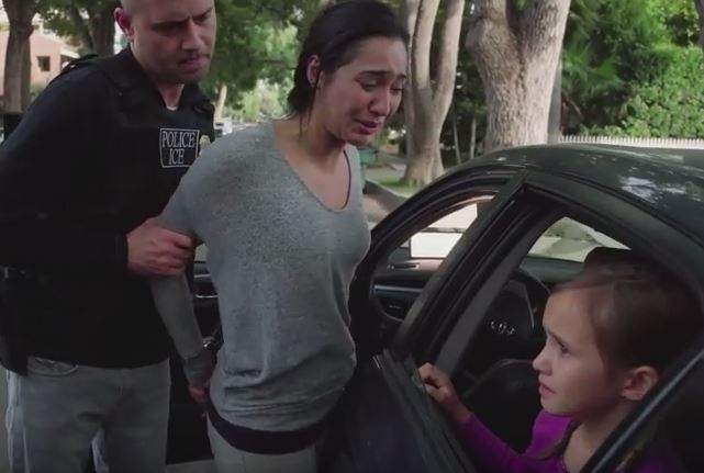 A still from the ad, in which an ICE agent forces a mother out of her car while her child watches from the vehicle.