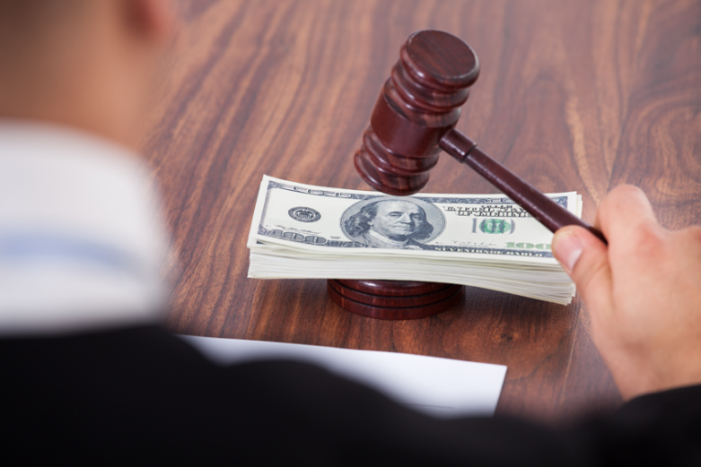 judge with gavel and stack of paper money on desk