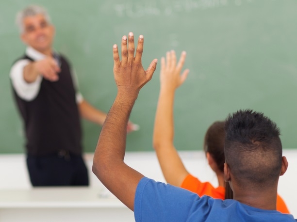 Students raise hands in classroom