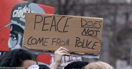 A sign held up at a protest in support of George Floyd that reads "Peace does not come from Police".