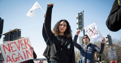 Young woman of color raises fist at an anti-gun rally.