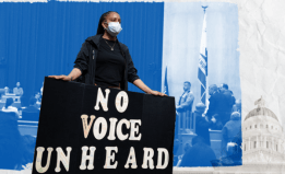 Activist holding poster that reads "No Voice Unheard"