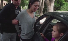 A still from the ad, in which an ICE agent forces a mother out of her car while her child watches from the vehicle.