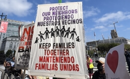 Protest sign reading "Protect our neighbors, keep families together" in English and Spanish