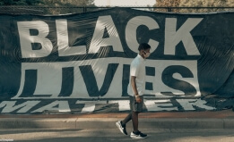 Black student walks by Black Lives Matter sign