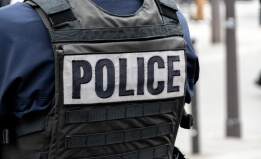 A person wearing a bulletproof vest with the word police across the back. 