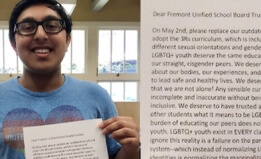The author stands in their school library, holding their letter to the school district and smiling at the camera