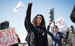 Young woman of color raises fist at an anti-gun rally.