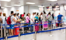 A crowd of people wait in line for security screening at an airport.