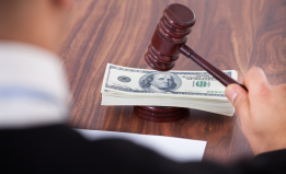 judge with gavel and stack of paper money on desk