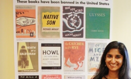 Laila Fahimuddin stands in front of an ACLU poster featuring banned books such as Howl and Native Son