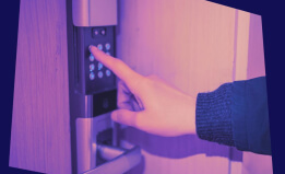 A finger presses a button on a digital door lock 
