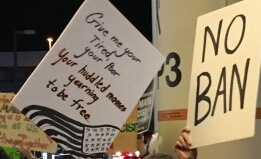 Signs at SFO protest read "No Ban"
