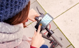 Woman operating mobile application standing atop scooter