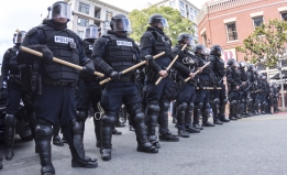 Police in riot gear, holding batons, on a California street