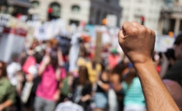raised fist in forground at a protest 