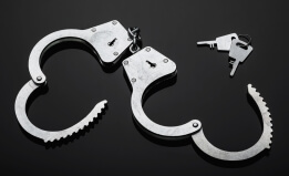 Silver handcuffs against black background.