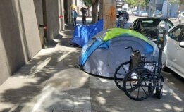 wheelchair beside a tent on a street in San Fransisco 
