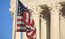 American flag waving in front of the U.S. Supreme Court building columns on Capitol Hill in Washington, DC