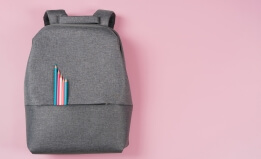 backpack on pink background with pencils in pink and blue
