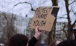 person holding a sign that says "Protect trans youth"