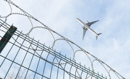 airplane flying over barbed wire