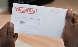 Close-up Of Person's Hand Holding Overdue Notice