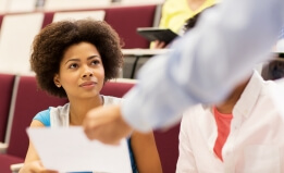 Black woman being handed a piece of paper in a classroom