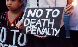 Black sign with white writing reading "No To Death Penalty."