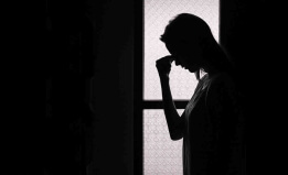 backlit photo of woman holding her forhead in despair
