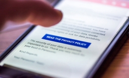 A photograph of a person scrolling on their phone to read the privacy policy of a website