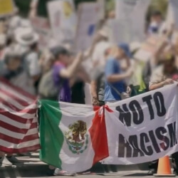 protestors holding the US and Mexico flags and a "No To Racism" sign