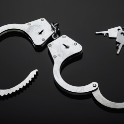 Silver handcuffs against black background.