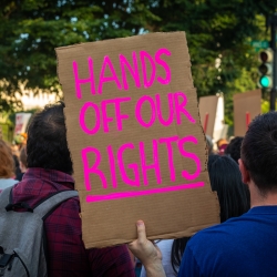 Protestor holds sign reading "Hands off our Rights"