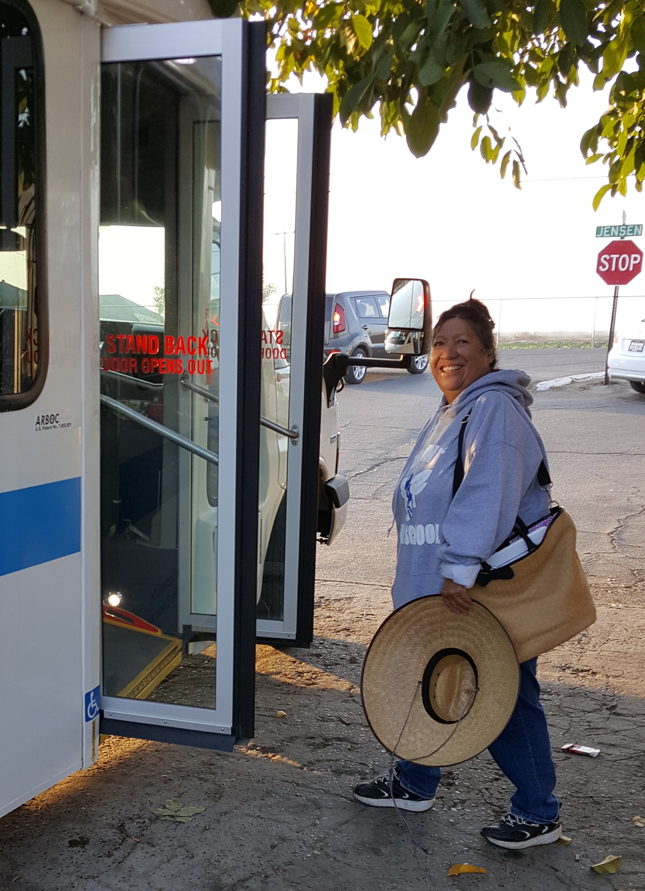 Woman steps on to bus, smiling